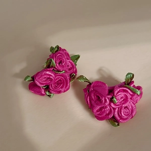 Close-up of handmade rose red fabric flower earrings with green leaves and pearl accents