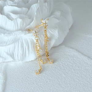 Detail of gold butterfly tassel earrings with sparkling crystals on a floral surface