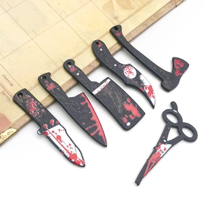 Macro shot of 6 acrylic Halloween charms featuring blood-stained knives and axes on paper