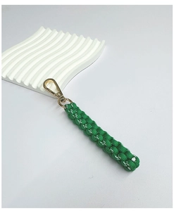 Close-up of green and white handmade braided keychain with a gold lobster clasp