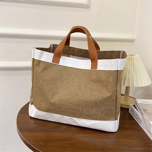Large capacity linen tote bag with leather handles and white trim on a wooden table