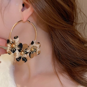 Close-up of leopard print fabric flower hoop earrings on model with golden metal plating