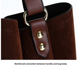 Close-up of the suede bag with reinforced stitching and golden metal rivets on the handle
