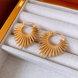 Detailed close-up of golden sunburst heart earrings displayed in a luxury gift box