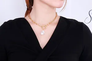 Close-up of vintage gold chunky chain necklace with baroque pearl on a female model