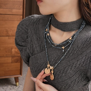 Detail of vintage gold embossed coin pendants on multi-strand beaded long necklace