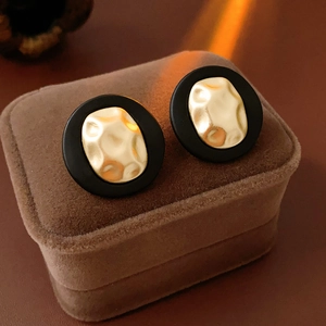 Detail of vintage gold textured metal disc earrings on black base set in jewelry box