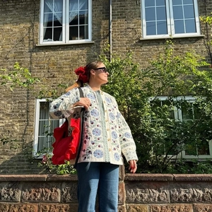 Detailed shot of floral quilted jacket with blue flowers and red fruit embroidery pattern