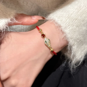 Gros plan du bracelet en corde tressée rouge avec serpent doré et zircons sertis