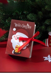 Detailed view of book-shaped Christmas candy gift box with Santa motif and red ribbon