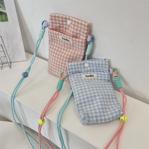 Détail des sacs de téléphone en tissu à carreaux avec cordes tressées et boutons pression