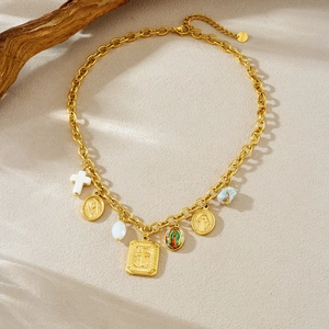 Detail of gold chain necklace with white cross and layered coin pendants on wood