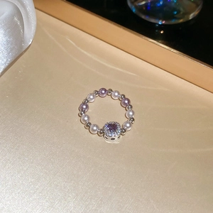 Detailed macro view of a beaded ring with purple zircon and white pearls on gold tray