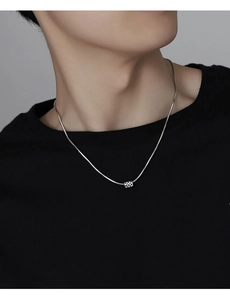 Close-up of a silver titanium steel necklace with a square checkered pendant on a model