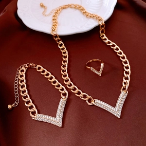 Macro shot of gold V-shaped crystal necklace, bracelet and ring set on silk