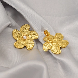 Detail of vintage gold flower earrings with textured petals and a pearl center on silk