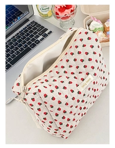 Dettaglio della trousse trapuntata bianca con motivi a fragola e chiusura a zip robusta
