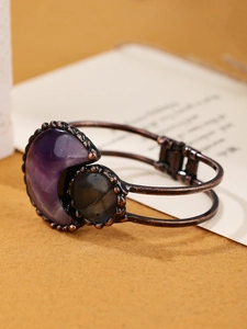 Detail view of a bohemian bronze bangle with purple moonstone and dark round gems