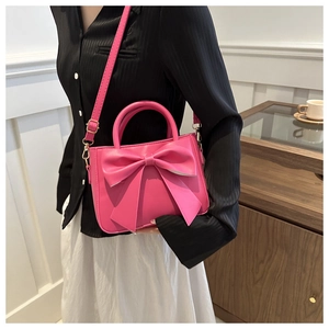 Chic pink handbag with a large decorative bow shown on a shoulder in a modern room