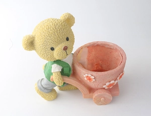 Dettaglio del vaso per fiori in resina a forma di orso con carriola rosa e fiori