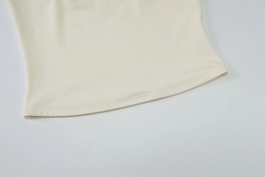 Detailed macro view of high-quality sewing craftsmanship on a cream halter top hem