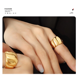 Detail eines breiten, vergoldeten Edelstahlrings mit eleganter Wellentextur