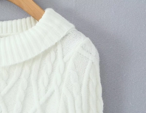 Close-up of white cable knit sweater detailing collar, shoulder, and fuzzy texture