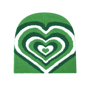 Detailed close-up of the green and white heart-shaped jacquard knit texture on the beanie