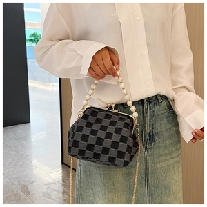 Detail of checkered clip bag with large pearl handle and gold metal chain strap