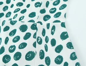 Macro view of white fabric with green polka dots showing fine stitching and texture