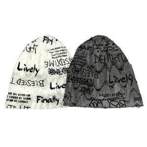Detail view of distressed knit beanies with graffiti print and ripped texture effects