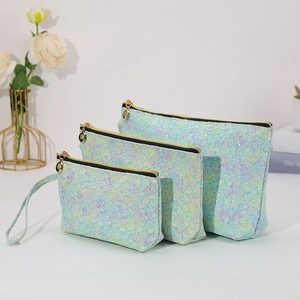 Set of three iridescent green makeup bags with lace texture and gold zippers for travel