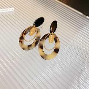 Macro shot of minimalist tortoiseshell resin and gold metal layered geometric earrings