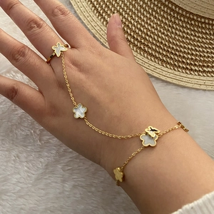 Dettaglio del bracciale ad anello dorato con farfalla e quadrifoglio in madreperla