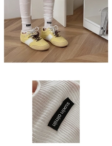Macro shot of white ribbed knit leg warmers with branded woven label detail