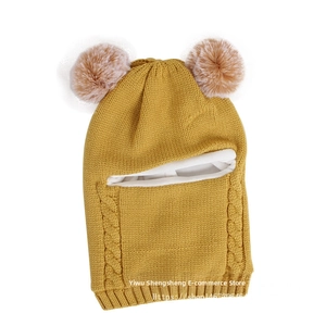 Detail of yellow knit balaclava for kids with two pom-poms and warm white fleece lining