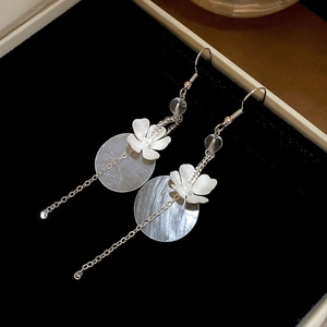 Detail of floral earrings with shell discs and chain tassels on black velvet box