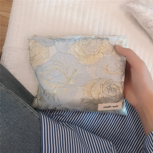 Detailed macro of golden rose jacquard fabric and brand label on small makeup bag