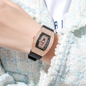Macro shot of tonneau-shaped rose gold diamond watch with black rubber strap detail