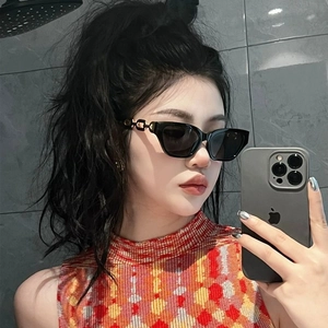 Close-up of black cat-eye sunglasses with gold metal chain temple on a model's face
