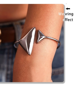 Close-up of polished stainless steel open bangle with geometric triangle accents on wrist