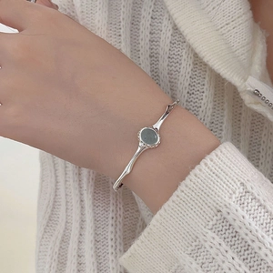 Detail of silver bamboo texture bracelet featuring a round dark green gemstone inlay