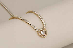 Detailed view of heart-shaped pendant with sparkling pavé crystals on a gold tennis chain