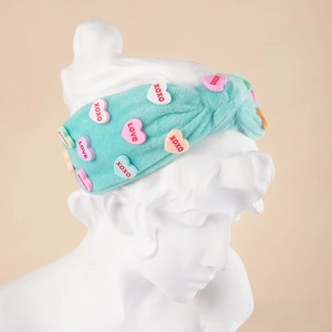 Detail of light blue plush headband with colorful XOXO heart patches on a bust