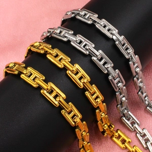 Detail of gold and silver chunky link chain jewelry set displayed on a cylindrical stand