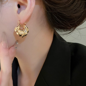 Close-up of golden croissant shell earrings on model with polished metallic texture