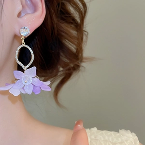 Elegant long earrings with sparkling zircons and layered purple flower petals on model