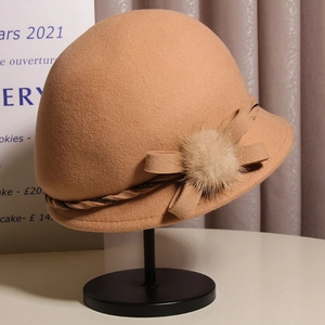 Detail of wool cloche hat with fabric bow, beige pompom and decorative bead chain