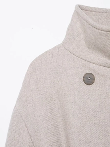 Dettaglio del cappotto di lana grigio chiaro con collo alto e trama del tessuto