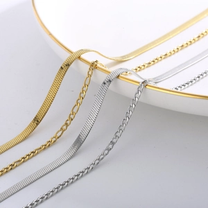 Detailed macro view of gold and silver snake and figaro chain necklaces on a ceramic plate